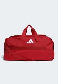 Bolso de deporte rojo con forma rectangular, hecho de tejido duradero. Presenta un logo blanco, asas dobles y una correa de hombro ajustable.
