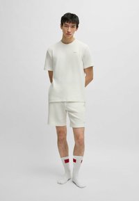 Witte textuur korteg mouw shirt en bijpassende shorts, beide met een subtiel ruitjespatroon. Witte sokken met rode logo accenten.