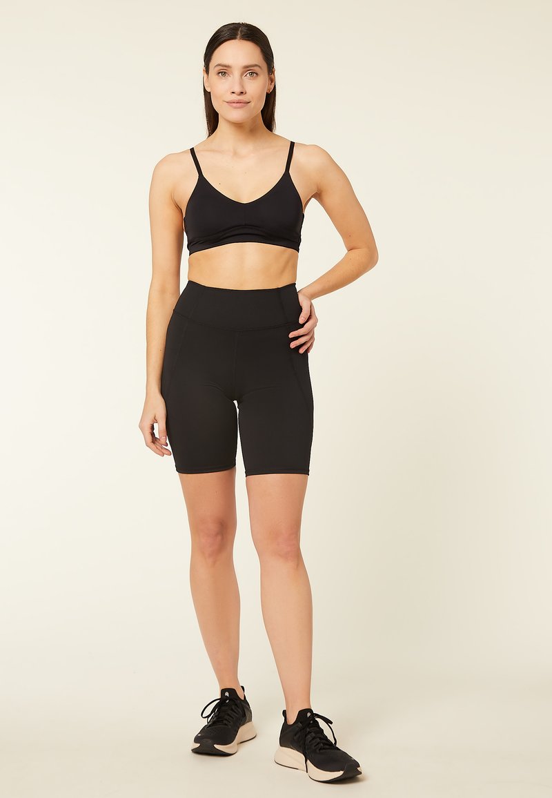 Sujetador deportivo negro y pantalones cortos de ciclismo negros de cintura alta. Tela elástica con textura suave. Ajuste cómodo, ideal para actividades atléticas.