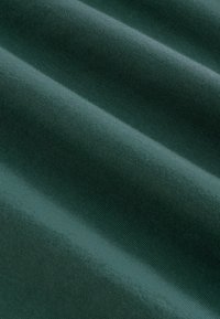 Temnozeleno blago z gladko teksturo, ki ima rahlo svetliko in mehke valovite gube. Material se zdi, da je bombaž ali bombažna mešanica.