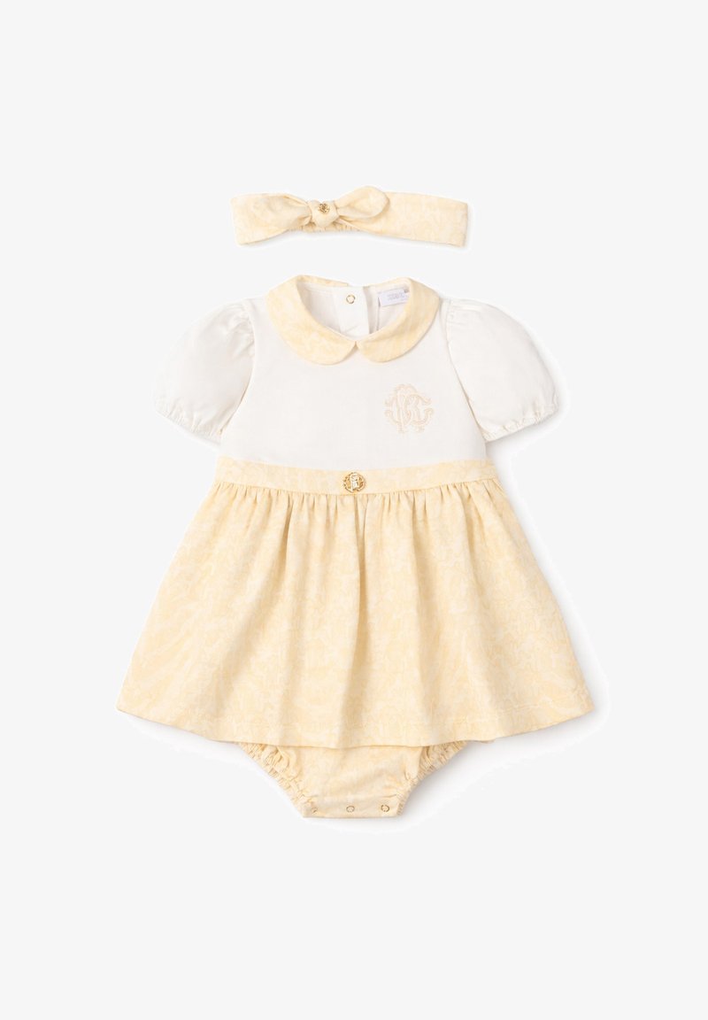 Robe bébé crème et jaune pâle avec manches bouffantes, col Claudine, bloomer assorti et bandeau avec nœud, décorée d'un motif subtil et d'un emblème.