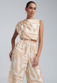 Combinaison légère, beige et blanche avec une coupe décontractée, ornée d'un imprimé zèbre, d'une taille élastique et sans manches.