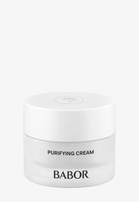 Pot rond en verre avec un corps lisse et transparent et un couvercle blanc. Le texte indique "CRÈME PURIFIANTE" et "BABOR" en lettres noires en gras.