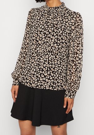 Schwarz-creamfarbige Leopardenmuster-Bluse mit hohem Kragen, langen Ärmeln und gerafftem Detail am Hals. Kombination mit einem schwarzen, ausgestellten Rock.