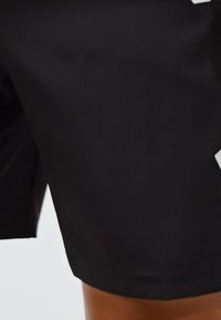 Schwarze Sportshorts aus leichtem Stoff. Bieten eine lockere Passform, eine glatte Textur und ein seitliches Logodetail in kontrastierendem Weiß.