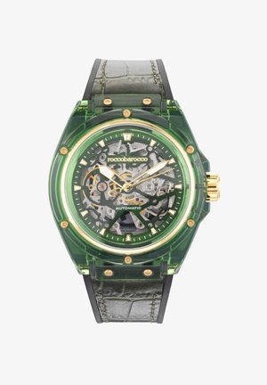 Reloj verde transparente con un diseño esquelético, acentos en oro y una correa de cuero negra. Presenta una caja redonda y mecánica de movimiento visible.