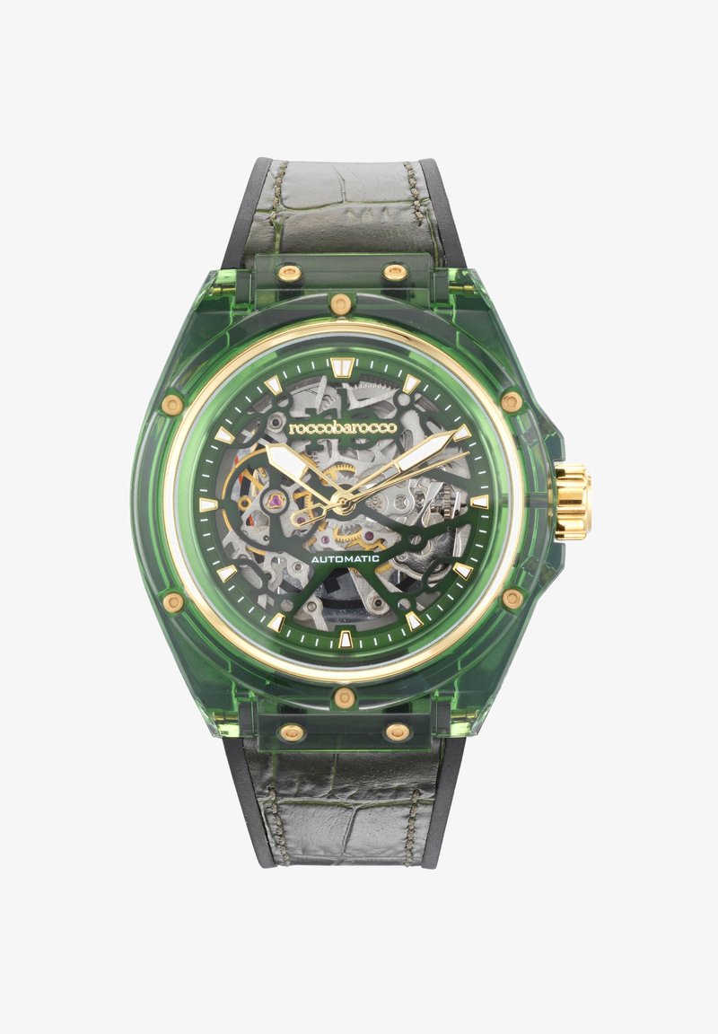 Roheline läbipaistev kell, millel on skeleti disain, kuldsed aktsendid ja must nahkrihm. Omab ümmargust korpust ja nähtavaid liikmehanikaid.