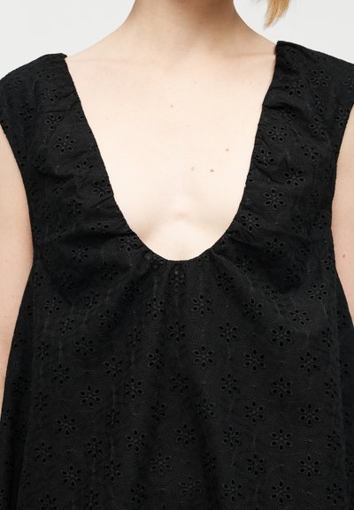 Μαύρο φόρεμα από κεντημένο ύφασμα με βαθιά V-λαιμόκοψη, κοντά μανίκια και ρευστή σιλουέτα με λουλουδάτα σχέδια.