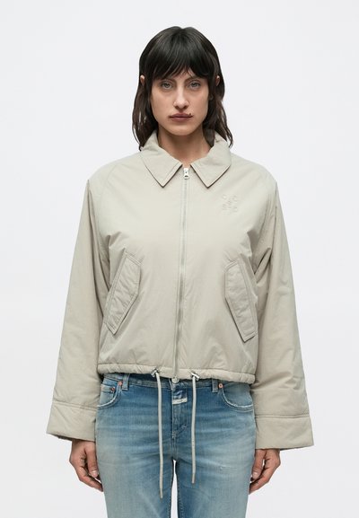 Veste courte gris clair avec col, fermeture éclair à l'avant et deux grandes poches frontales. Comprend une taille à cordon et un marquage subtil.