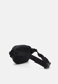 Black waist bag with a smooth fabric exterior, padded mesh accents, adjustable strap, and a side clip for securing. Compact, rounded shape.