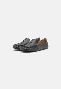 Sorte læder loafers har en samlet tekstur, guldfarvede hardware-detaljer og en fleksibel gummisål. Slank design med rund tå.