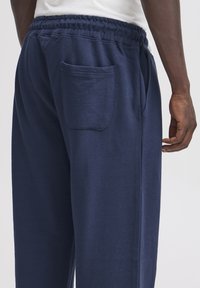 Mörkblåa sweatpants i bomullsblandning med resår i midjan, med en enkel bakficka och avslappnad passform.