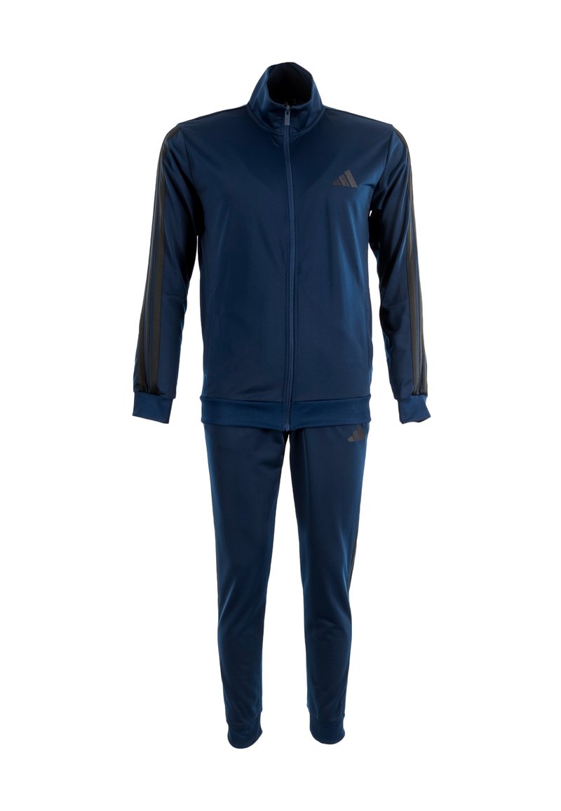 Survêtement bleu marine en tissu lisse et extensible ; comprend une veste zippée avec un col haut et un pantalon assorti avec des accents latéraux.