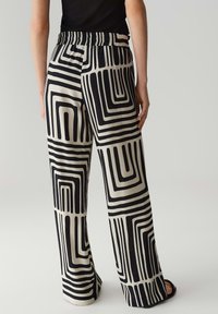Wijdvallende broek met een zwart en beige patroon van in elkaar grijpende rechthoeken, met een elastische tailleband en een soepele textuur.