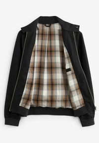 Veste noire à fermeture éclair avec doublure intérieure à carreaux marron et beige, ouverte pour montrer le motif à carreaux à l'intérieur et les poignets côtelés.
