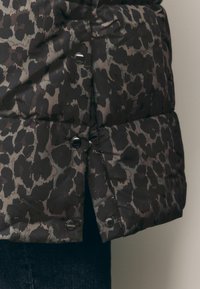 Kvalitetna crna jakna s jastučićima, sivo-leopard uzorka, sa metalnim kopčama i glatkom, sjajnom površinom.