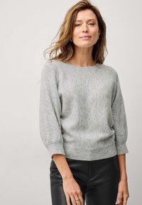 Pull en maille gris clair avec un col rond, des manches trois-quarts et des bords côtelés. Texture lisse, ajusté à la taille.