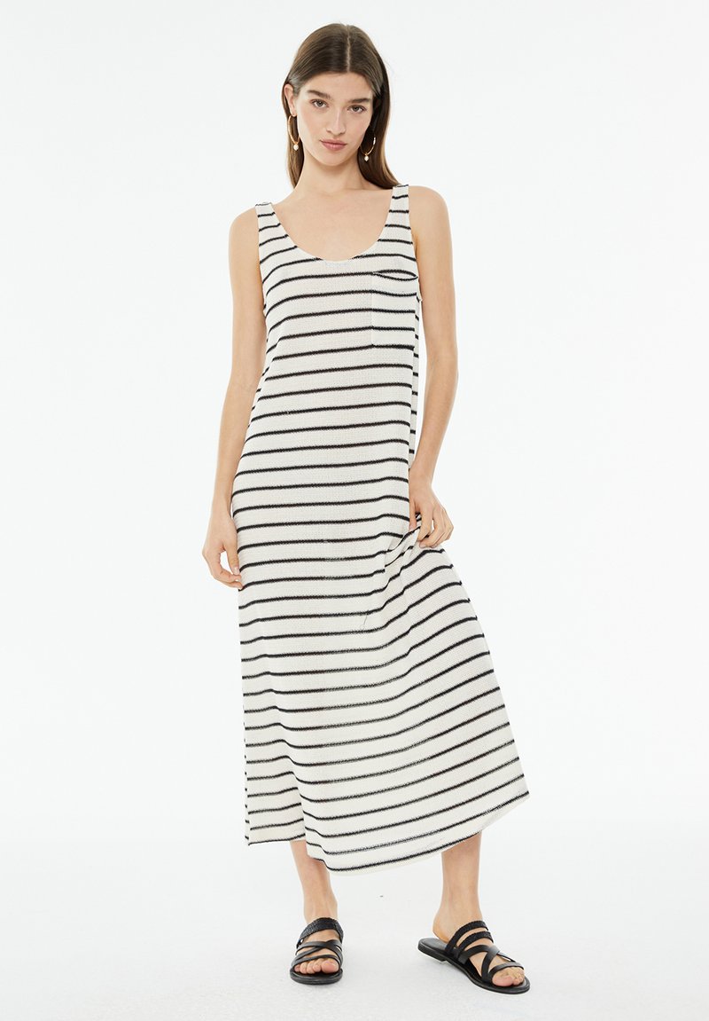 Gestreiftes ärmelloses Maxikleid in Weiß und Schwarz. Mit Rundhalsausschnitt und kleiner Brusttasche. Weicher, leichter Stoff.