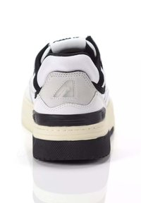 Sneaker bianco e nero con suola in gomma testurizzata, collo imbottito e dettagli in pelle scamosciata. Presenta un logo sul tallone con un colore a contrasto.