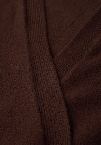 Brown knitted fabric, featuring a textured surface with varying stitch patterns, including smooth and ribbed sections. Soft and warm appearance.