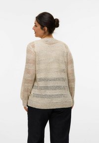 Cardigan lavorato a maglia beige con strisce orizzontali a rete, maniche lunghe e orlo a coste. Tessuto testurizzato con leggera lucentezza.