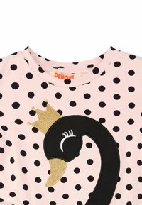 Vaaleanpunainen pilkullinen T-paita, jossa on mustan joutsenen kuvio kultakruunun ja valkoisten yksityiskohtien kanssa. Pehmeää puuvillakangasta, pyöreä pääntie.