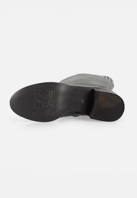 Suela de bota de cuero negro con agarre texturizado, con un estampado de logo y tamaño 37. El tacón está ligeramente curvado para un diseño elegante.
