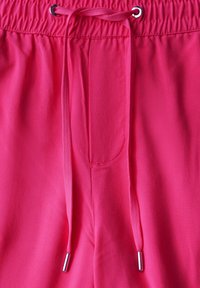 Klart rosa shorts med elastisk midja, med en dragsko försedd med silverfärgade metallspetsar och horisontell sömnadsdetalj upptill.