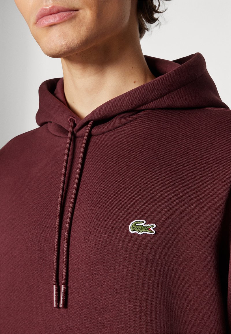 Burgunderfarbene Kapuzenpullover aus einer Baumwollmischung, mit einer Kängurutasche, Kordelzügen und einem kleinen bestickten Krokodil-Logo auf der Brust.