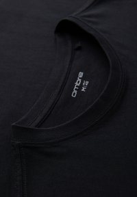 T-shirt noir à col rond avec étiquette de marque « ombre » visible et taille M/48 imprimée à l'intérieur de l'encolure.