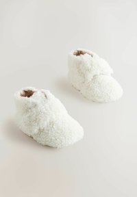 Vita fluffiga stövlar gjorda av mjukt material, med hög ankel och rund tås, samt en mjuk innersula för komfort.