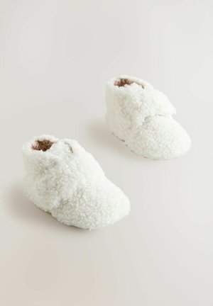 Bottines blanches duveteuses en matériau peluche, caractéristiques d'une cheville haute et d'une pointe arrondie, avec une doublure intérieure douce pour plus de confort.