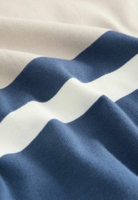 Striped fabric featuring creamy beige, white, and deep navy stripes. Soft texture with a subtle knit pattern, showcasing smooth transitions between colors.