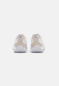 Scarpe da corsa Puma con una tomaia in mesh bianco e dettagli in suede beige, suola spessa bianca con grip testurizzato e logo sul tallone.