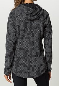 Hoodie à pois noirs et blancs avec une finition texturée, doté d'une capuche ajustée, de manches longues et d'un ourlet arrière plus long.