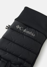 Juodas šiltas pirštines, turinčias siuvinėtą dizainą, raukšlėtą rankovę ir užtrauktuko kišenę, išorėje su sidabriniu Columbia logotipu.