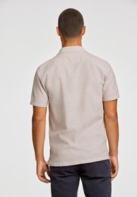 Short-sleeve beige shirt made of lightweight fabric, featuring a subtle texture, straight hem, and a classic collar design.