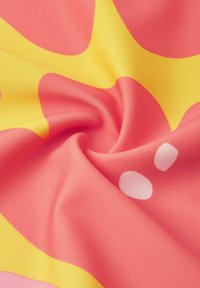 Textilstoff mit einem rosa Hintergrund und kräftigen gelben und weißen abstrakten Formen, der eine glatte Textur und lebendige Farben zeigt.