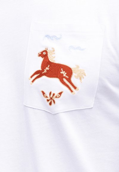 Λευκή υφασμάτινη τσέπη με κεντημένο κόκκινο άλογο, μπεζ χαίτη και ουρά, μπλε σύννεφα από πάνω και διακοσμητικό ανθισμένο μοτίβο κάτω.