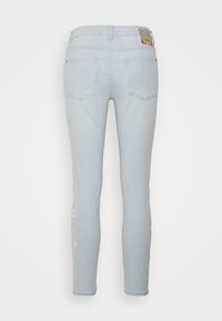 Jeans skinny às riscas azuis e brancas com um cós de altura média, bolsos traseiros e detalhes degradados nas laterais.