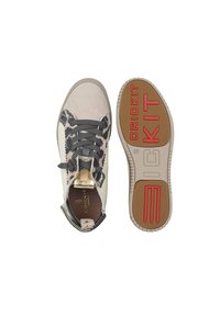 Sneakers met een beige en zwart patroon op de bovenkant, grijze veters, gouden accenten en een gestructureerde rubberen zool met "CRICKIT" in het rood.