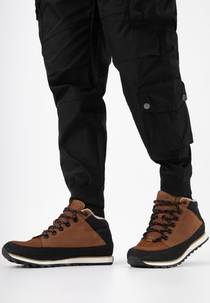 Bruine en zwarte hoge schoenen met een textuur oppervlak, voorzien van ronde veters, een gewatteerde kraag en een contrasterende witte tussenzool.