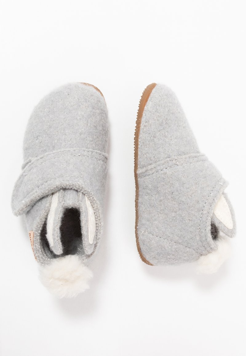 Sive papuče s zaobljenim vrhom, podesivim preklopom i smeškim gumiranim đonom. Imaju mekani beli pompon detalj na leđima.