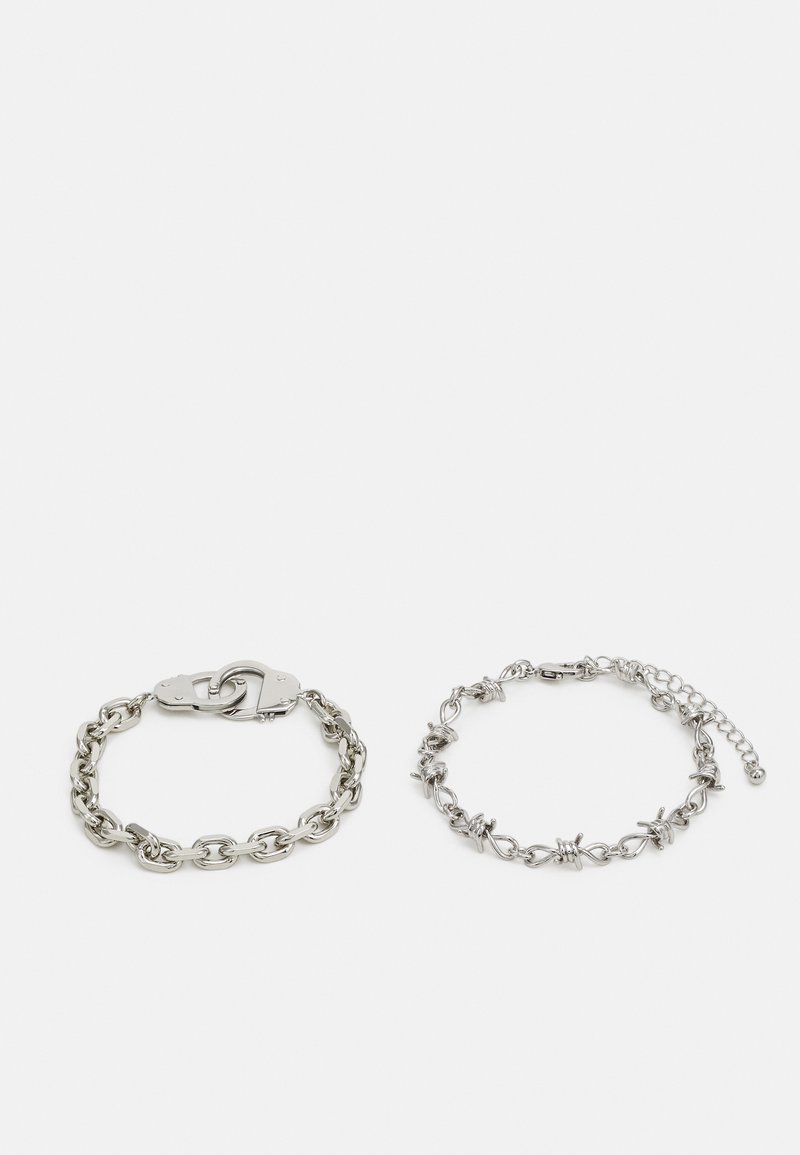 Silver chain bracelet with handcuff clasp on the left; right features a decorative chain with accents. Both have a polished finish.
