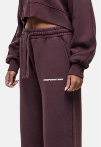 Bordeaux sweatpants van zachte stof, met een elastische tailleband en witte logo-tekst "GOODFORNOTHING" op het linkerdij.