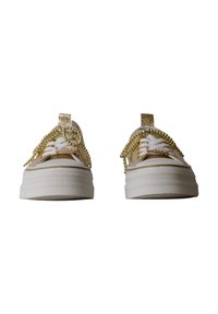 Baskets à plateforme beige avec lacets blancs décorés de chaînes de perles dorées et languettes pailletées, vues de face sur fond blanc.
