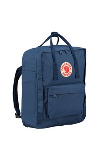 Zaino blu navy con forma rettangolare, realizzato in tessuto resistente, presenta una tasca frontale con zip e un logo rotondo iconico. Spallacci regolabili.