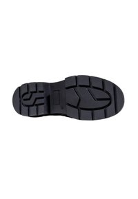 Suela de zapato de goma negra con patrones de banda de rodadura profundos que incluyen formas rectangulares y geométricas para mayor agarre y durabilidad.
