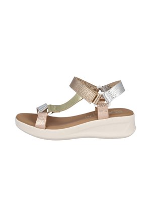 Sandalia de cuña para mujer con suela blanca, tiras de cuero en tonos metálicos rosa dorado, dorado y plateado, punta abierta y cierre ajustable en el tobillo.