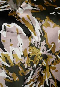 Gemusterter Stoff in einer Mischung aus Schwarz, Beige, Braun und Weiß, mit glatter Textur und abstrakten floralen Designelementen.